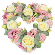 A full, heart-shaped floral wreath dominates the image, resting against a clean white background that highlights its soft colours and intricate workmanship. The heart form is complete and symmetrical, filled edge to edge with blossoms so that it looks lush and comforting, like a floral embrace. Cream and pale yellow roses form the main structural points of the design, their velvety, spiralled petals opening in generous, rounded blooms that speak of loyalty, devotion, and gentle respect. Threaded among them are numerous pastel pink carnations, clustered closely so that their frilled, multi-layered petals create a delicate, textured surface that softens every contour of the heart. Deeper tones come from magenta and mauve lisianthus blooms dotted throughout, their more open, cup-like shapes and slightly rippled edges adding visual interest and a romantic, almost dusk-like richness. Silvery-green eucalyptus leaves are interlaced between the flowers, their smooth, rounded foliage cooling the palette and providing a fresh, herbal backdrop that defines the heart's edges with subtle grace. Tiny yellow-green buds emerge here and there, fresh and tightly furled, symbolising new beginnings and quiet hope within a tribute meant for farewell. The overall mood is tranquil, tender, and reflective, making this heart wreath an ideal choice for funerals, memorials, or graveside tributes in and around Primrose Hill. Whether placed in a local chapel, carried to a service near Chalk Farm, or ordered from Florist Primrose Hill for a family gathering at home, it offers a beautifully crafted, heartfelt expression of sympathy and enduring love.